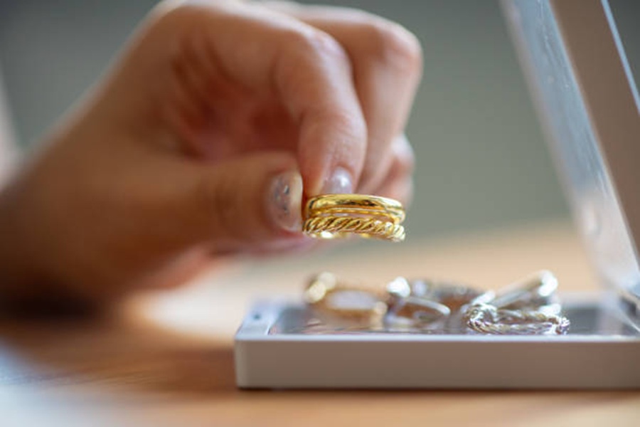 Women’s hands choosing golden ring from her jewelry box